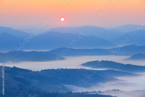 mountain chain silhouette in dense mist at the sunrise