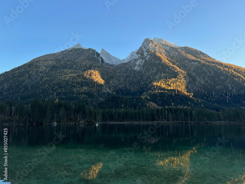 Lake Hintersee in Ramsau bei Berchtesgaden features crystal-clear waters reflecting the Bavarian Alps, surrounded by lush forests and rugged rocks—a serene, picturesque alpine escape.