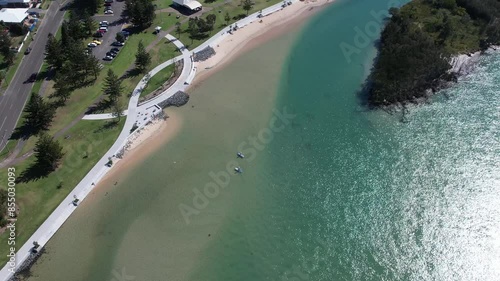 Panoramic aerial establishing orbit of sandy beach and promenade walking path in Windang NSW Australia photo