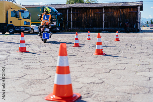 L-driver person drives slalom through the orange cones on motordrome on motorcycle photo