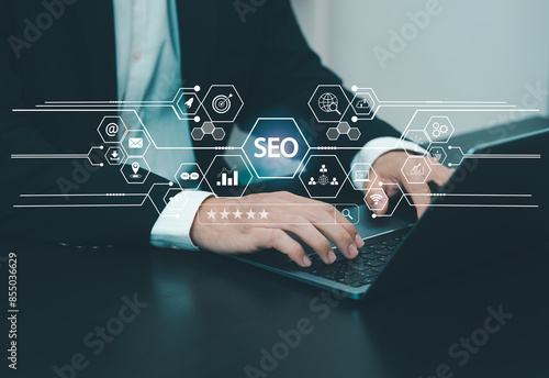 Businessman presses on laptop keyboard to use search engine (SEO) to find customers or promote and advertise online content for marketing technology and business solutions.