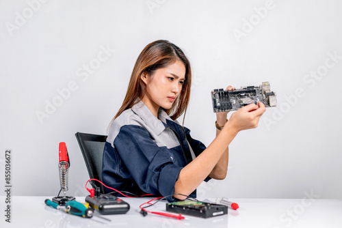 Wallpaper Mural Beautiful young repair engineer holds the electronic circuit board of a computer with a gray background. Female technician repairing a computer Torontodigital.ca