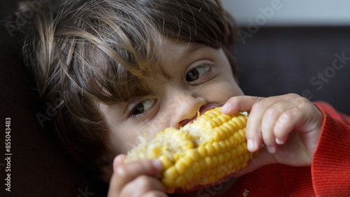 Foto Young Boy Biting Into a Juicy Corn Cob - Close-Up View