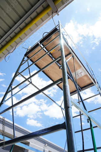 Scaffolding . Mobile metal scaffolding with small wheels and a safety helmet on them. Work continues.