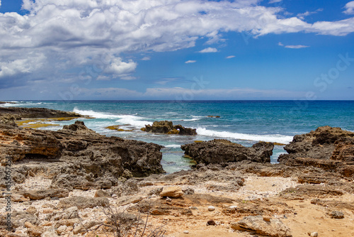 Waves crashing on rocky shore with clear blue sky in Hawaii. photo