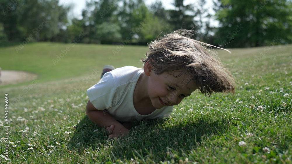 Young Boy Joyfully Crawling Through Grassy Field in Sunlit Park Young Boy Joyfully Crawling Through Grassy Field in Sunlit Park