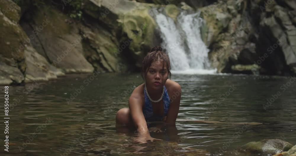 On Trinidad's island, a bikini-clad young girl enjoys the waterfall and river. On Trinidad's island, a bikini-clad young girl enjoys the waterfall and river.