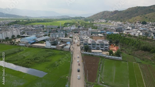 Drone footage panning over a small village next to the crop fields cultivated by the traditional Bai Tribe. The vast mountains and Er Hai encapsulate this area, offering serenity to the visitors. photo