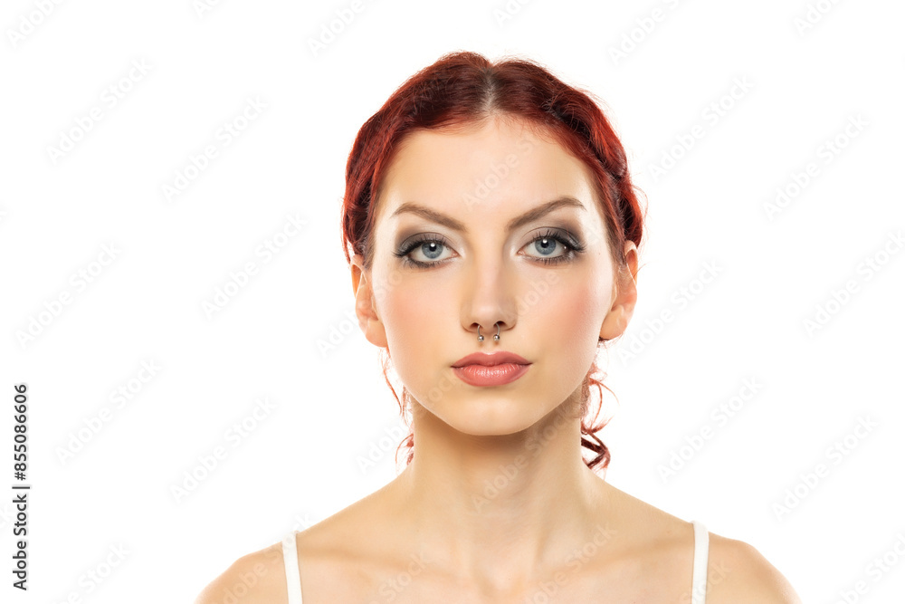 Portrait of a young serious woman with makeup and nose piercing on a white background