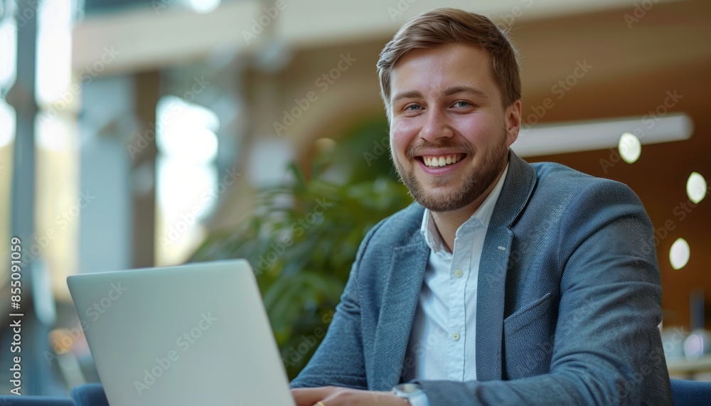 Smiling Businessman Working on Laptop in Modern Office Smiling Businessman Working on Laptop in Modern Office