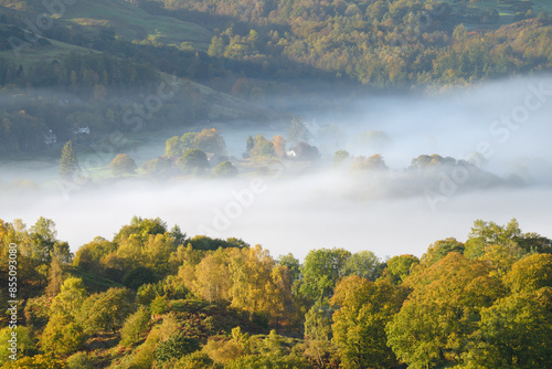 Mist in Lake District valley with beautiful Autumn colours. View from Loughrigg Fell overlooking Elterwater. photo