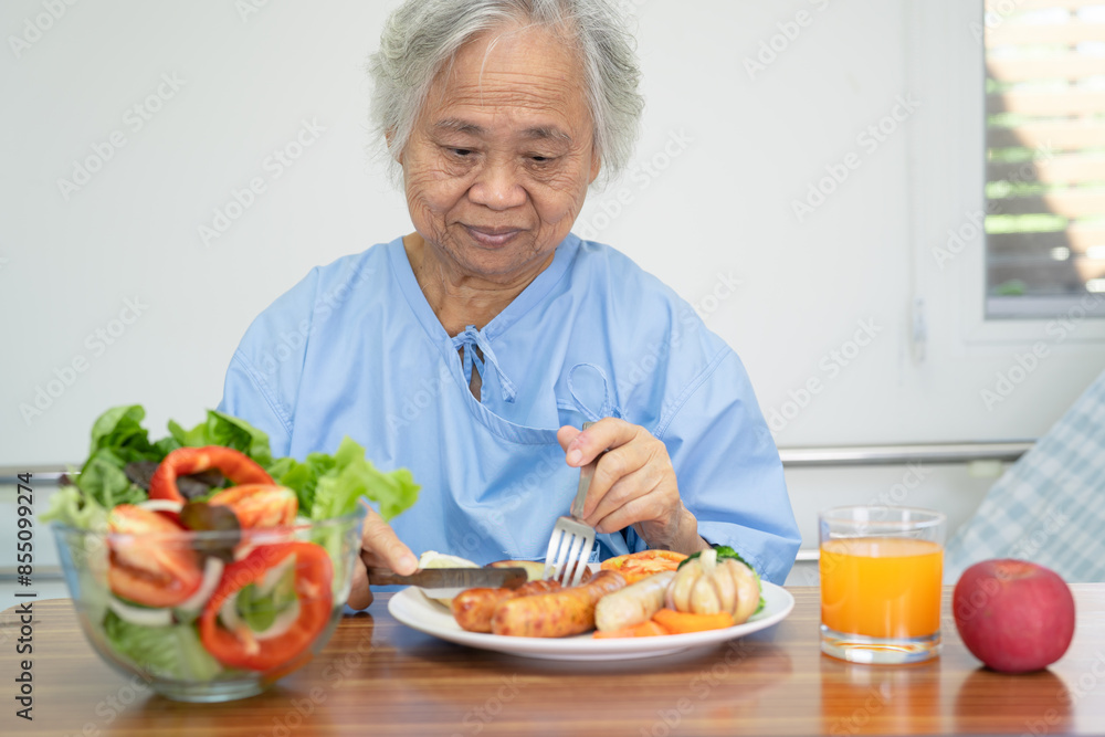 Asian senio woman patient enjoy eating breakfast with vegetable healthy food while sitting and hungry on bed in hospital. Asian senio woman patient enjoy eating breakfast with vegetable healthy food while sitting and hungry on bed in hospital.