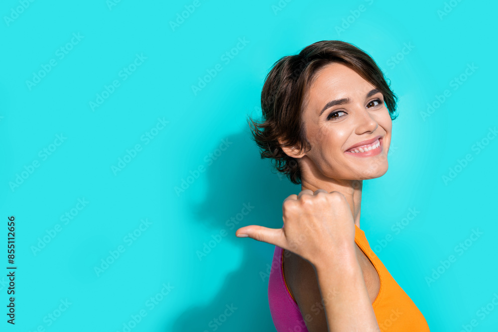 Fototapeta premium Photo of cute cheerful lady dressed colorful top showing thumb back empty space isolated turquoise color background