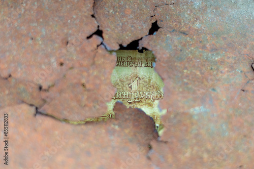 A piece of paper with the word "druzhba" on it is seen through a hole in a rusty