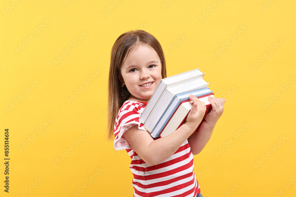 Cute little girl with books against orange background Cute little girl with books against orange background