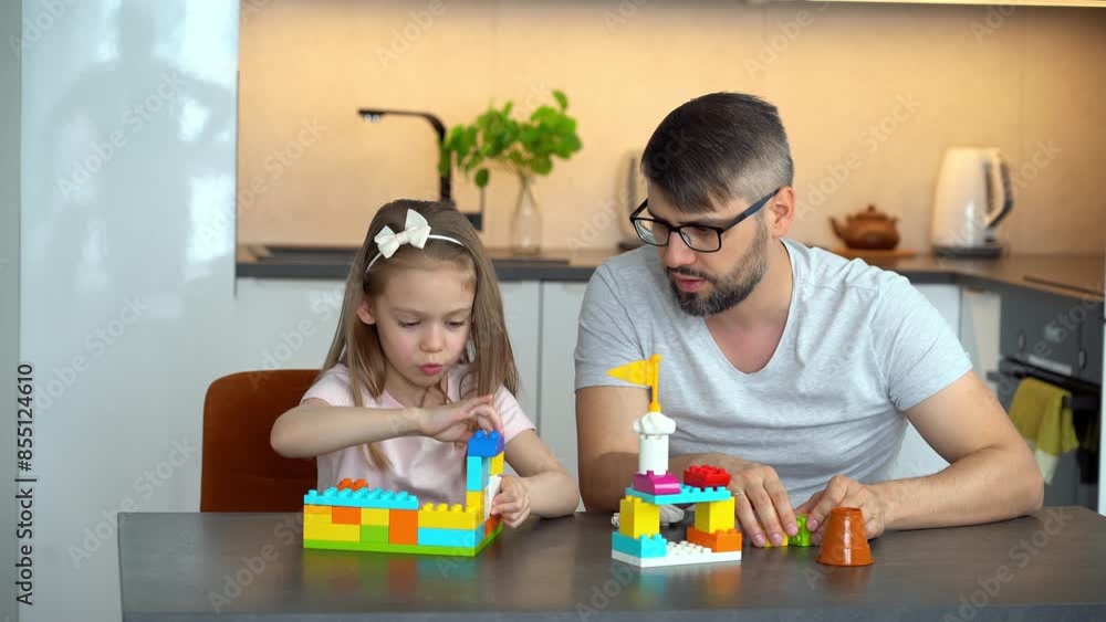 Father and daughter build plastic brick of construction set at home. Happy family play with construction kit. Leisure Father and daughter build plastic brick of construction set at home. Happy family play with construction kit. Leisure