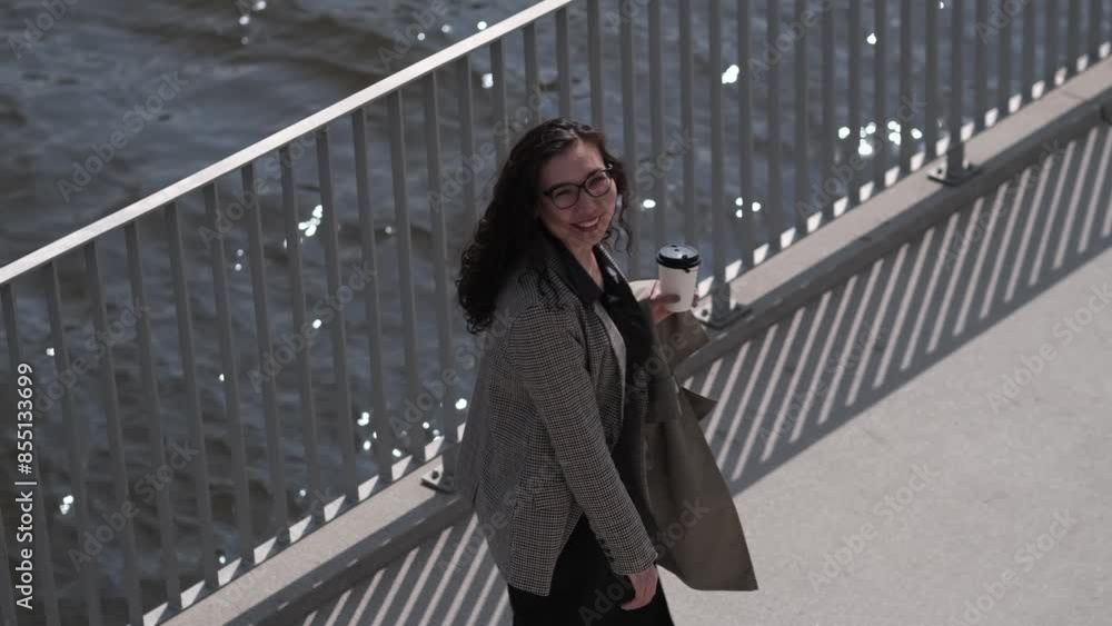 With a confident stride and a contented smile, she pauses on her morning walk to appreciate the serene water views from the bridge. With a confident stride and a contented smile, she pauses on her morning walk to appreciate the serene water views from the bridge.