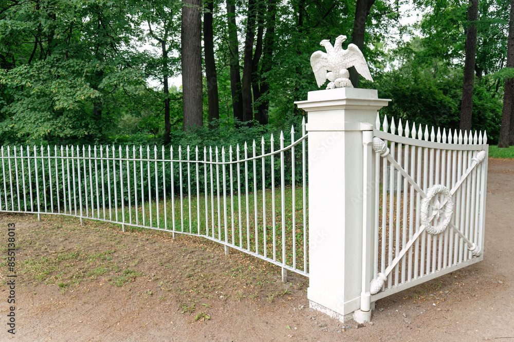The park fence in the city park with decorative gates decorated with eagles. The park fence in the city park with decorative gates decorated with eagles.