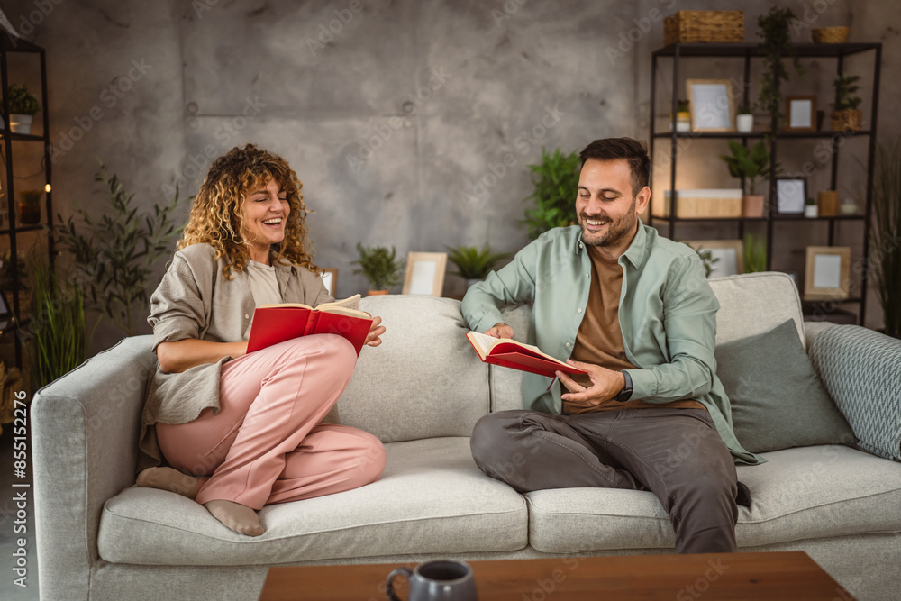 Obraz premium Boyfriend and girlfriend sit on sofa read book and discuss about that