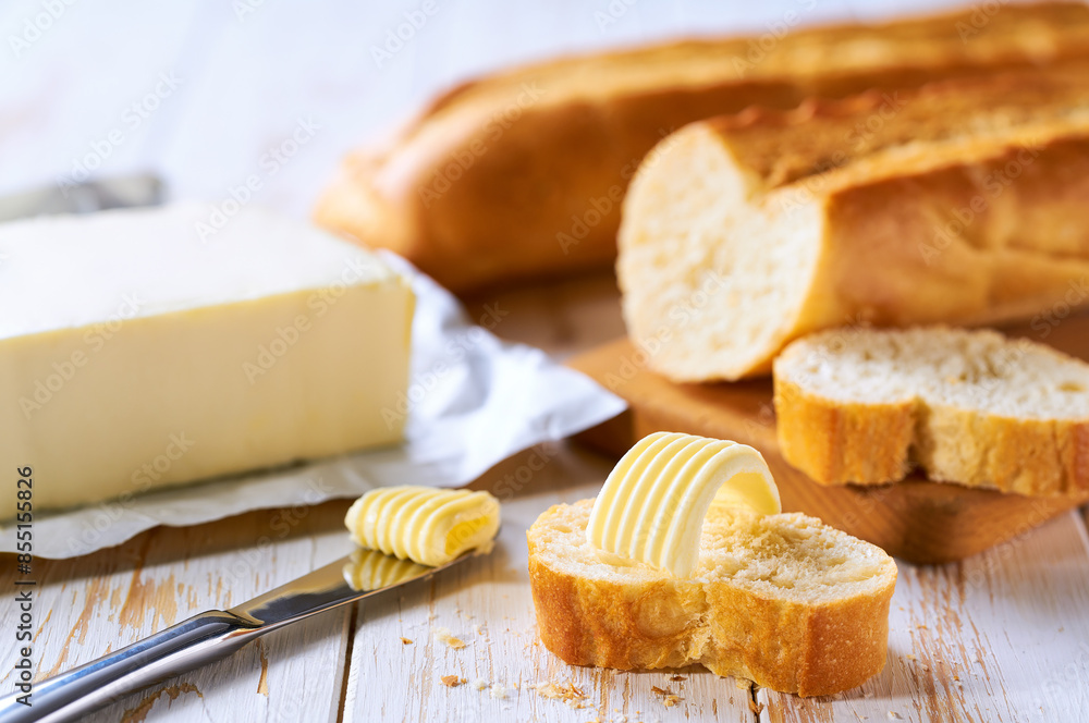 Cut slice baguettes with butter on a light kitchen table. Cut slice baguettes with butter on a light kitchen table.
