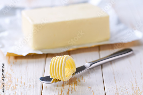 Tasty butter and knife on a kitchen table, selective focus. Butter curl on knife .