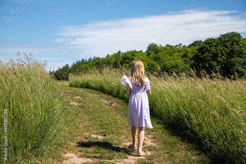 Girl walking on path through field in summer