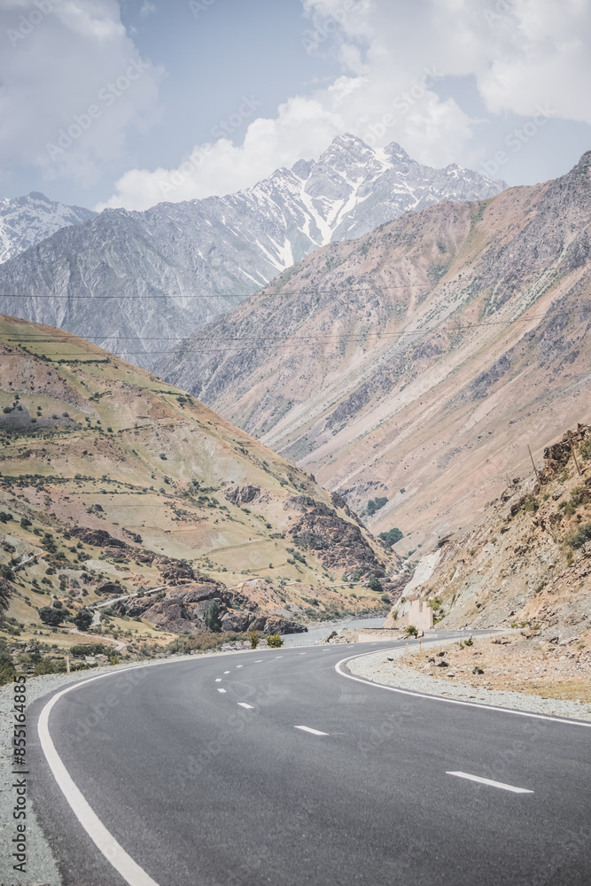 Automobile asphalt road in the mountains in the valley between rocky mountains, Pamir Highway in Tajikistan