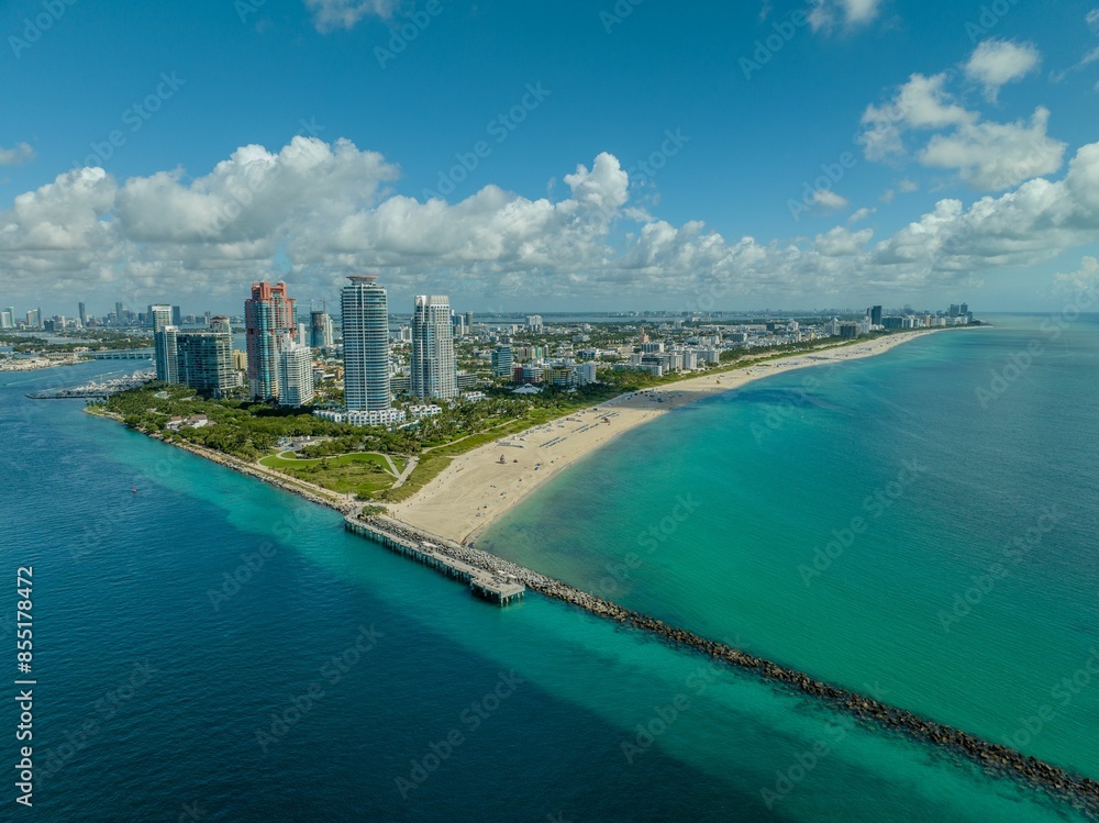 Aerial view of Miami Beach with high-rise buildings, a sandy beach, and ocean under a blue sky Aerial view of Miami Beach with high-rise buildings, a sandy beach, and ocean under a blue sky