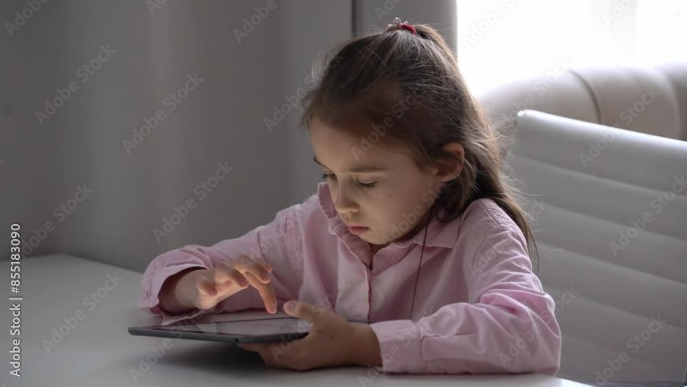 Girl Using Tablet. Intensely focused on a gadget. Caucasian school girl Engaged With Tablet in Bright Living Room Girl Using Tablet. Intensely focused on a gadget. Caucasian school girl Engaged With Tablet in Bright Living Room