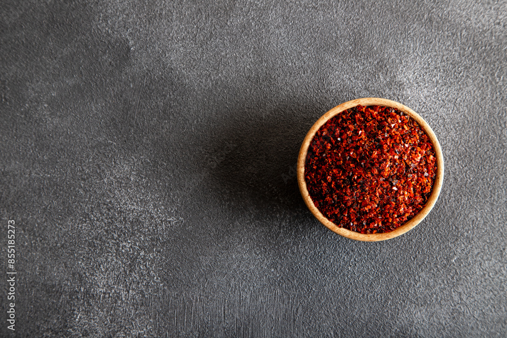 Red pepper flakes.Red chili peppers in wooden bowl on black background Red pepper flakes.Red chili peppers in wooden bowl on black background