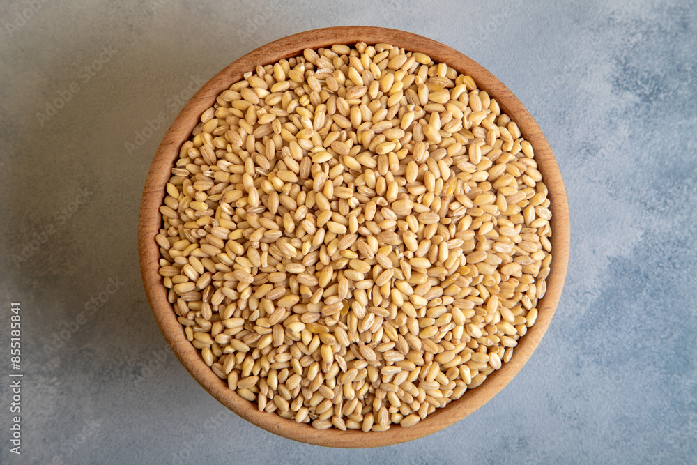 Wooden bowl in wheat grains on light blue background Wooden bowl in wheat grains on light blue background