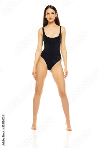 Young brunette woman in one piece bikini swimsuit posing on a whitestudio background. Front view.
