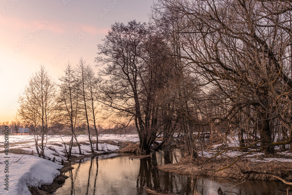 Obraz premium A snowy landscape with a river and trees