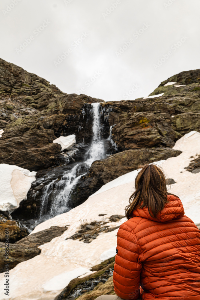 Girl sitting on her back looking at a waterfall Girl sitting on her back looking at a waterfall