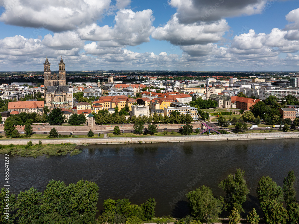 Fototapeta premium Shot of Magdeburg city center with cathedral and river Elbe. Tree-lined banks and cloudy sky over the city. Travel destination in Saxony-Anhalt Germany.