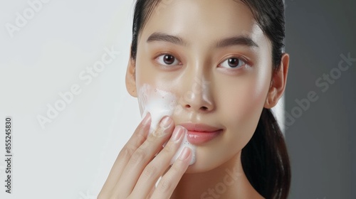 Asian model does facial cleansing young girl with foam on her face