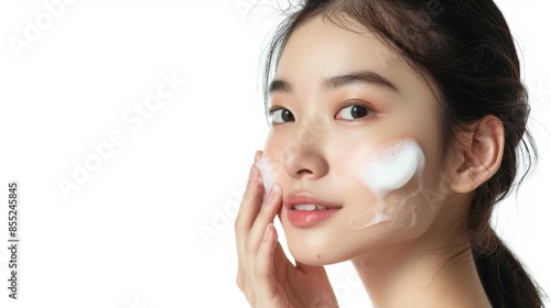 Asian model does facial cleansing young girl with foam on her face