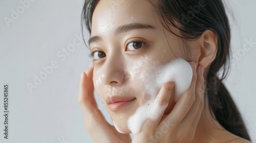 Asian model does facial cleansing young girl with foam on her face