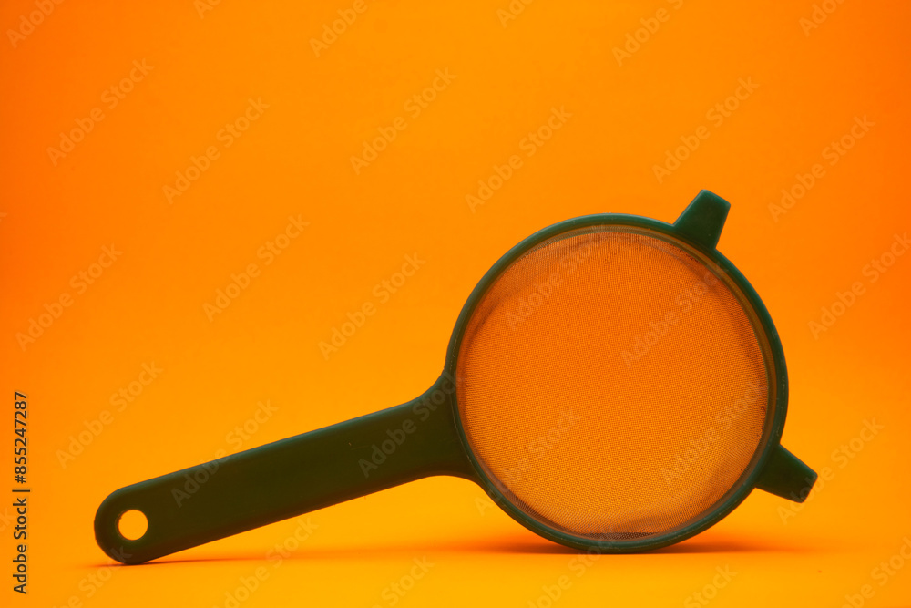 close up of a used green tea strainer on an orange background close up of a used green tea strainer on an orange background