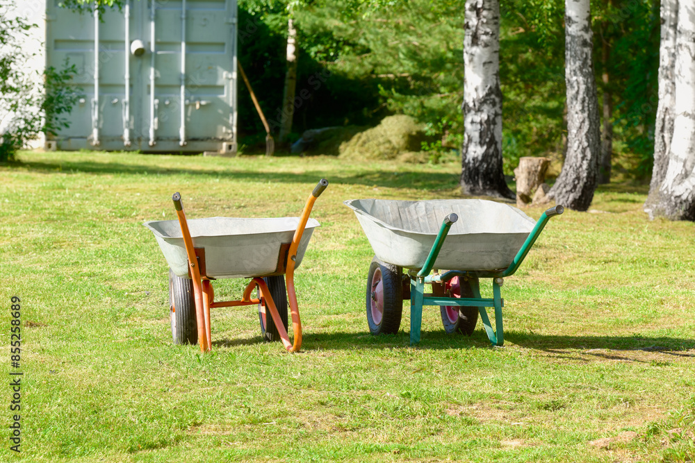 Two empty garden wheelbarrows on the mown grass. Two empty garden wheelbarrows on the mown grass.