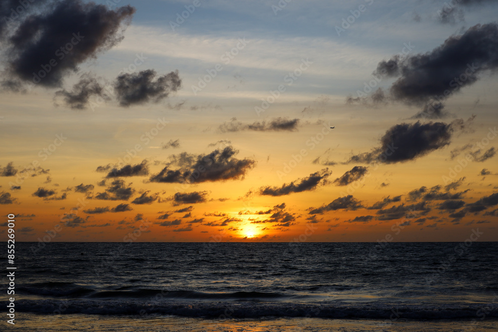 Sunrise on a beach, orange sun is shining through the dark clouds. Sea background for romantic travel Sunrise on a beach, orange sun is shining through the dark clouds. Sea background for romantic travel