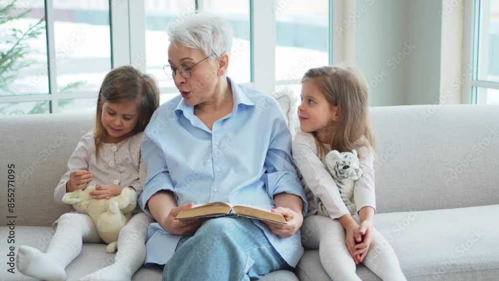 Happy family at home. Two girls sisters twins grandmother reading story book together. Good time at home. Grandma teaching granddaughters reading book fairytale telling story. Family generations Happy family at home. Two girls sisters twins grandmother reading story book together. Good time at home. Grandma teaching granddaughters reading book fairytale telling story. Family generations