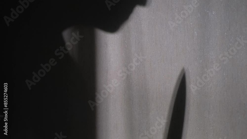 Silhouette of a man with a knife on the wall, close-up