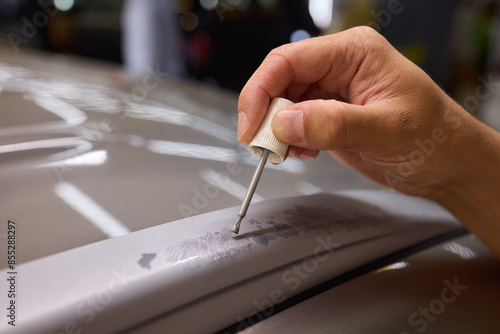 A man repaints a scratch on a car part in an auto repair shop with precision and craftsmanship photo