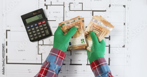 Worker counts money for building on calculator over floor plan drawing upper view. Engineer checks payment on printout of house apartment
