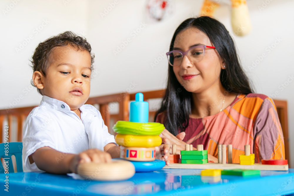 Fototapeta premium Single mother teaches her 2-year-old son to achieve goals with different educational games. Both are happy to be in this process full of love and patience while learning