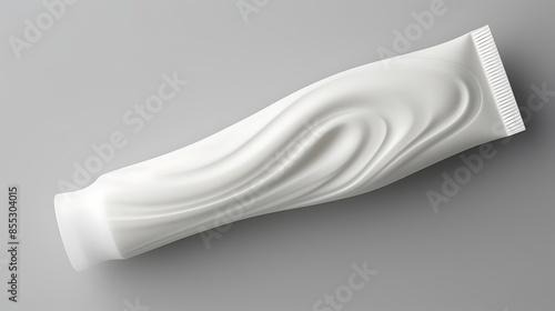 Close-up of a white tube of toothpaste on a gray background. The tube is slightly curved, with a smooth, glossy surface. photo