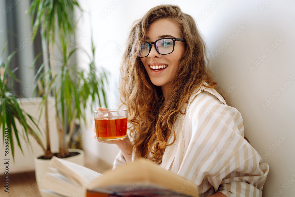 Pretty woman at home drinking tea and reading book or magazine. Domestic life. Pretty woman at home drinking tea and reading book or magazine. Domestic life.