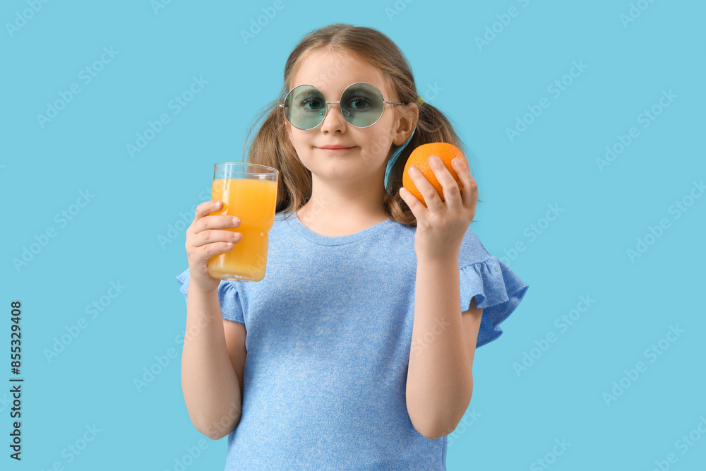 Cute little girl with glass of juice and orange on blue background Cute little girl with glass of juice and orange on blue background