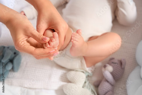 Mother massaging her baby's foot in crib, top view